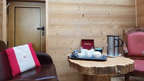 A wooden interior with a door, a table with a tray of white cups and a silver mug, and a red chair with a heart design. - Hotel De Geneve (Geneva)
