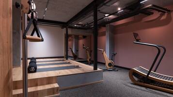 Un gimnasio moderno con suelo de madera, equipo de ejercicio y una escalera.