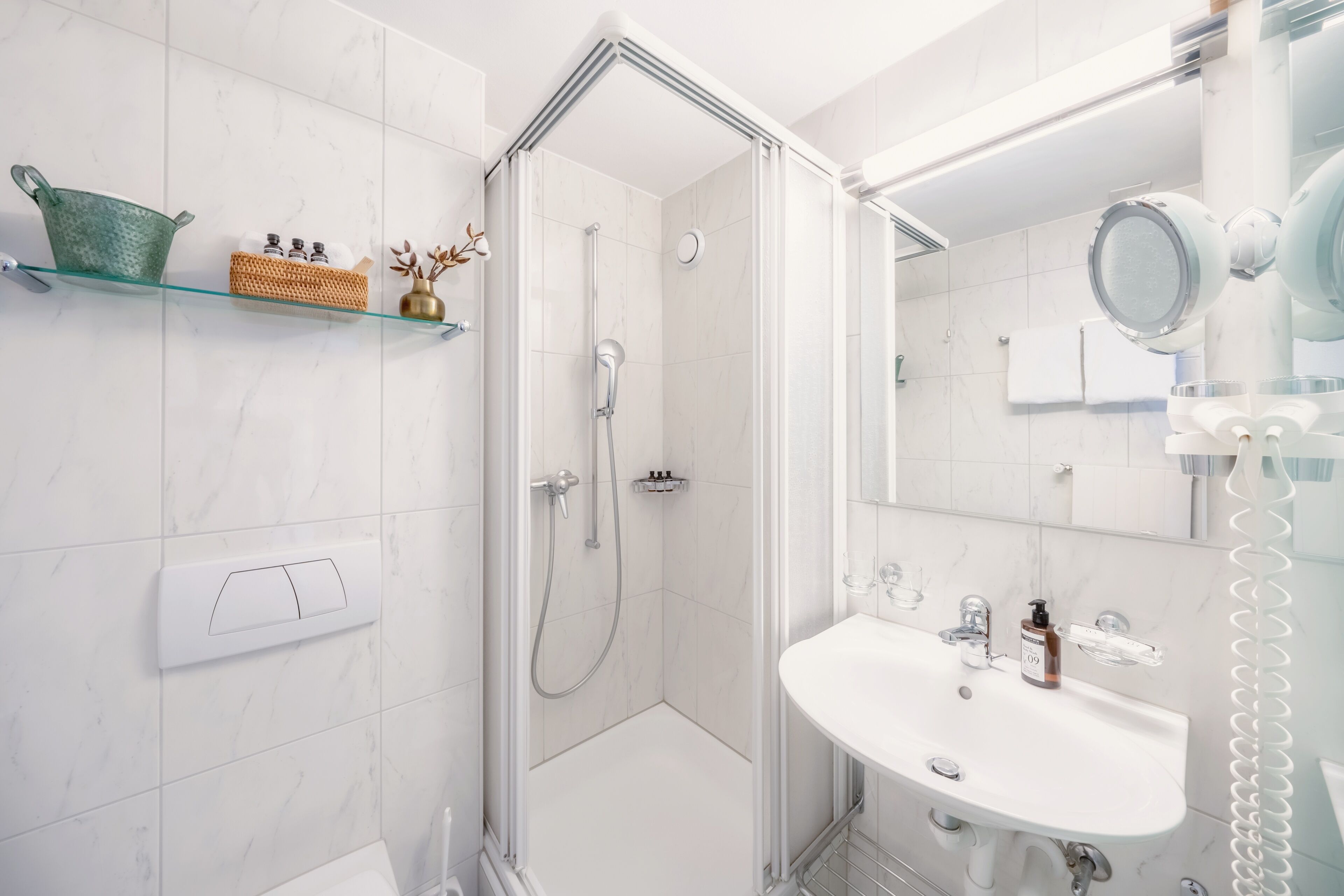 A modern bathroom with a glass shower enclosure, a white sink with a mirror, and a towel rack.