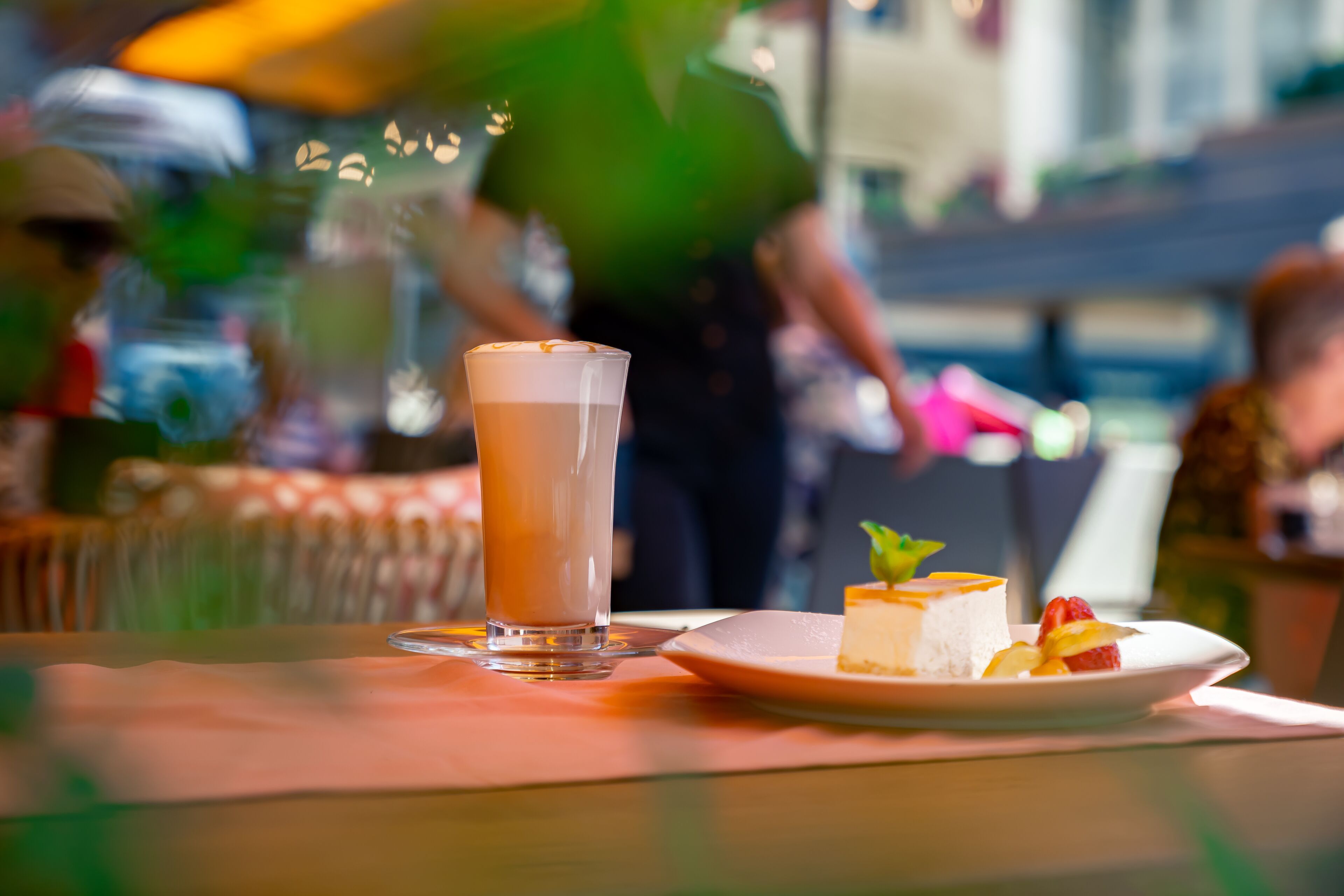 A table with a glass of iced coffee and a plate of dessert.