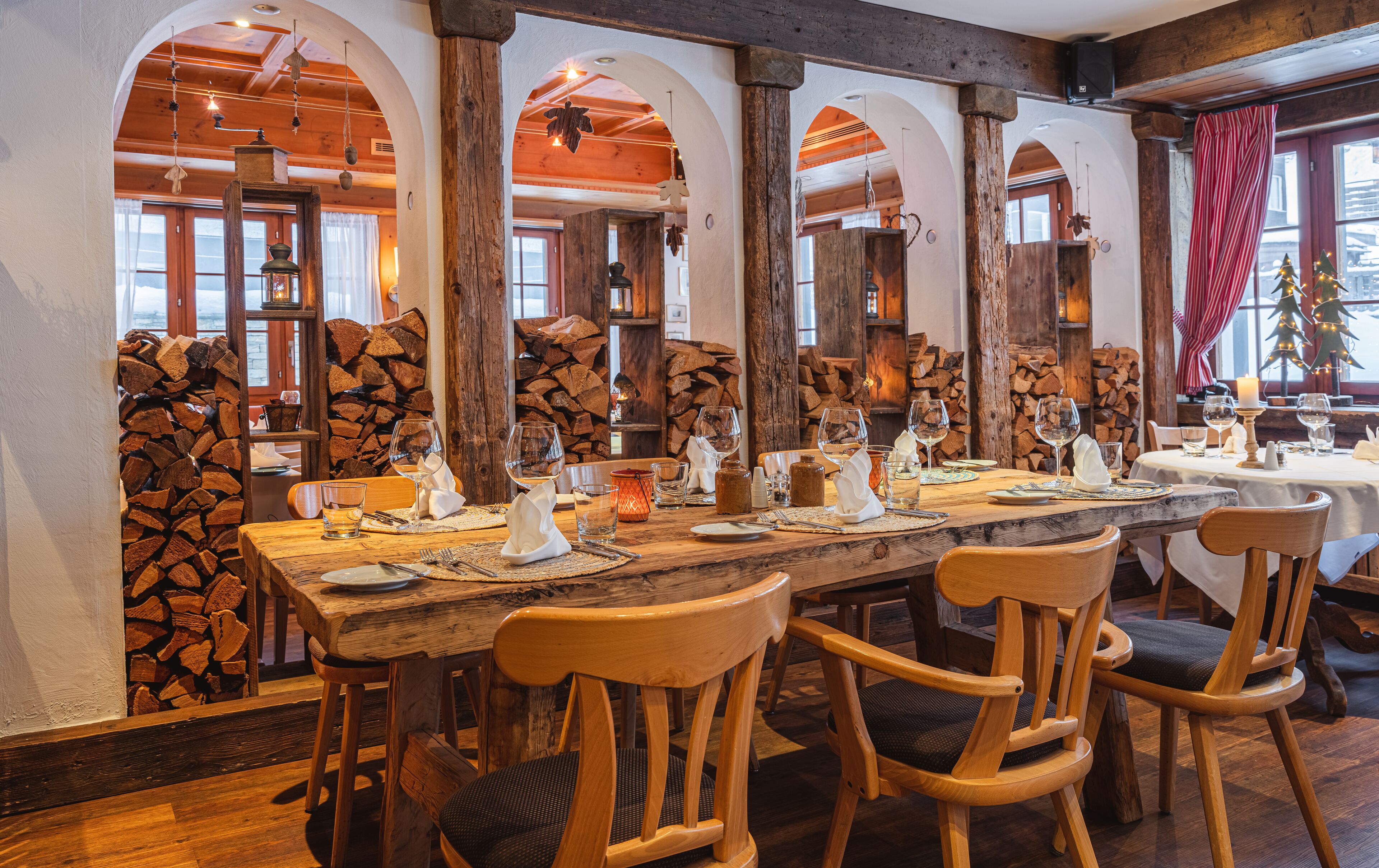 Un restaurant avec des tables et des chaises en bois, des plafonds en forme d’arc et un décor intérieur rustique.
