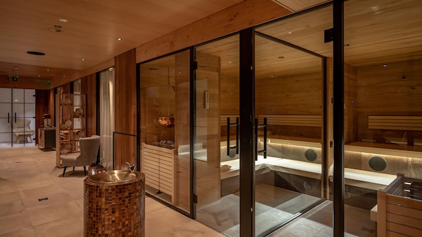 A modern spa room with wooden walls, a glass partition, and a large sink. - The Pollux (Zermatt)