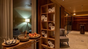 A modern interior with a wooden reception desk, a glass partition, and a seating area. - The Pollux (Zermatt)