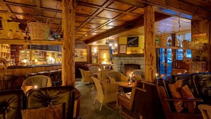 A cozy bar area with wicker baskets, a fireplace, and leather seating. - The Pollux (Zermatt)