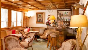 A cozy living room with wooden furniture, a bar area, and a painting on the wall. - Hotel Romantica (Zermatt)