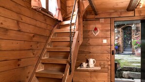 A wooden staircase leading to a room with a small table, a door, and a view of the outside. - Hotel Romantica (Zermatt)