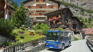 A hotel with a wooden facade, balconies with flower boxes, and a mountainous backdrop. - Hotel Romantica (Zermatt)