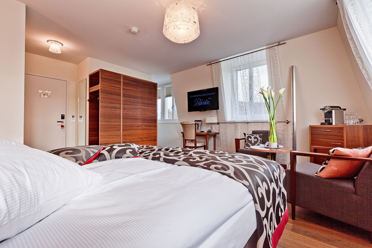 Una habitación de hotel con cama, escritorio, silla, televisor y armario.
