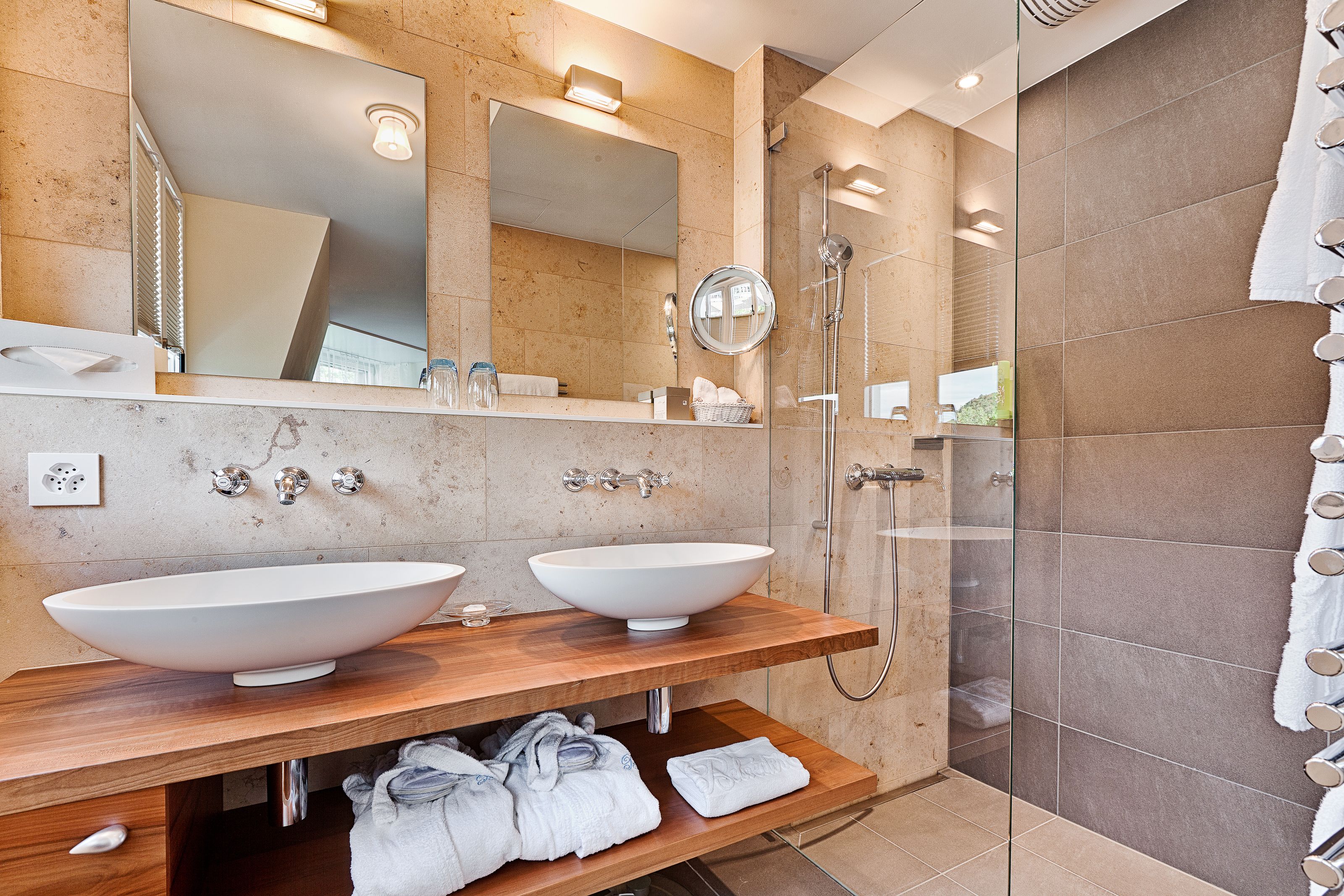 A modern bathroom with two large sinks, a glass-enclosed shower, and a large mirror.