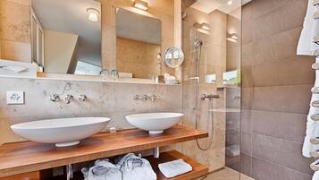 A modern bathroom with two large sinks, a glass-enclosed shower, and a large mirror.