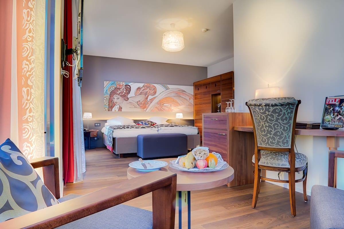 A modern hotel room with a bed, a desk, a chair, and a dining table.