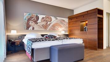 A modern bedroom with a large bed, bedside lamps, a desk, and a wooden wardrobe.