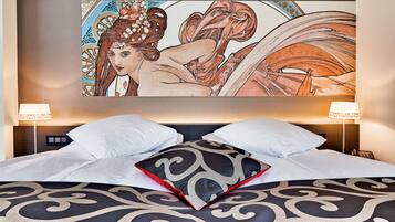 A hotel room with a large bed, two bedside lamps, and a large framed artwork on the wall.