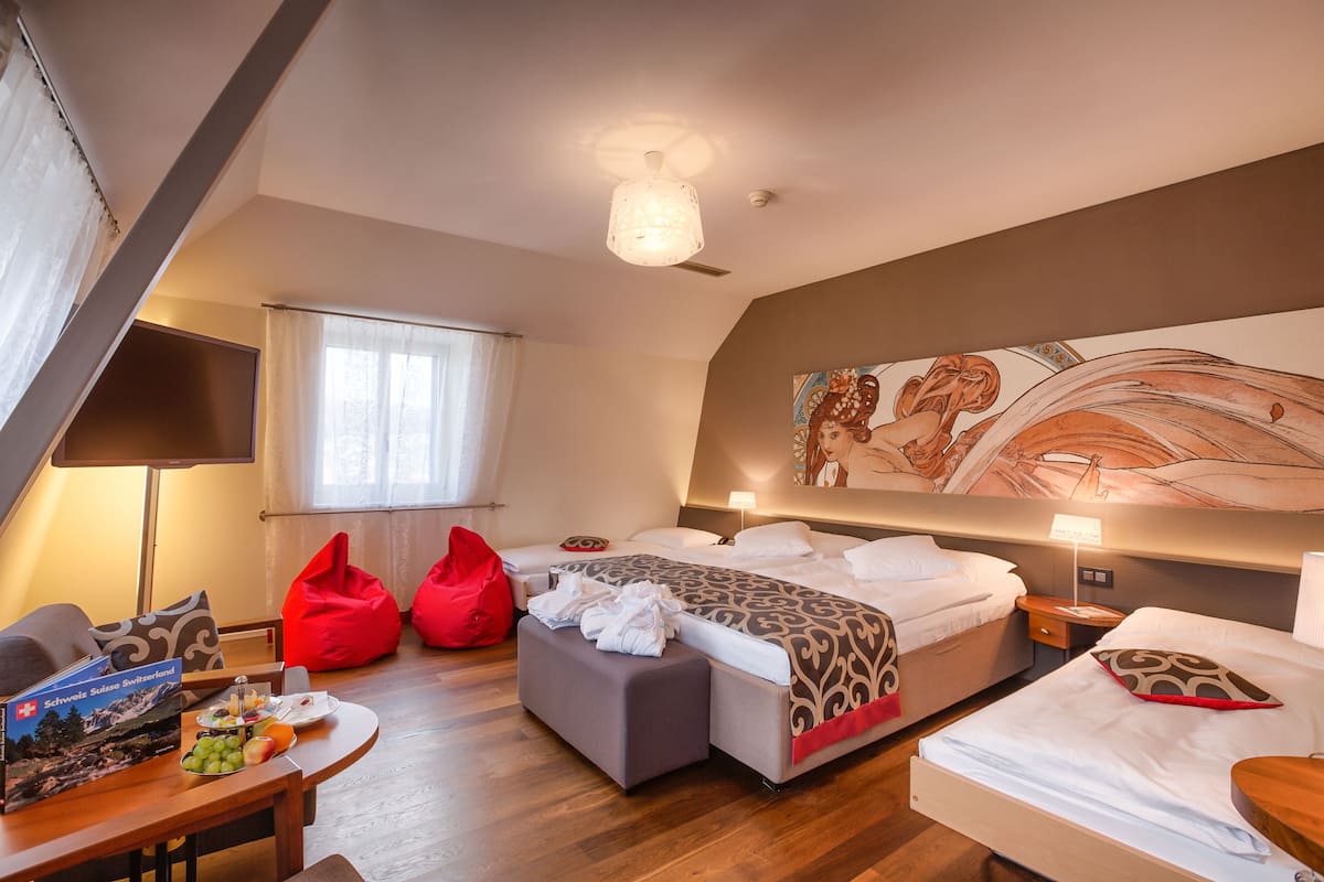 A modern hotel room with a large bed, a desk, and a seating area.