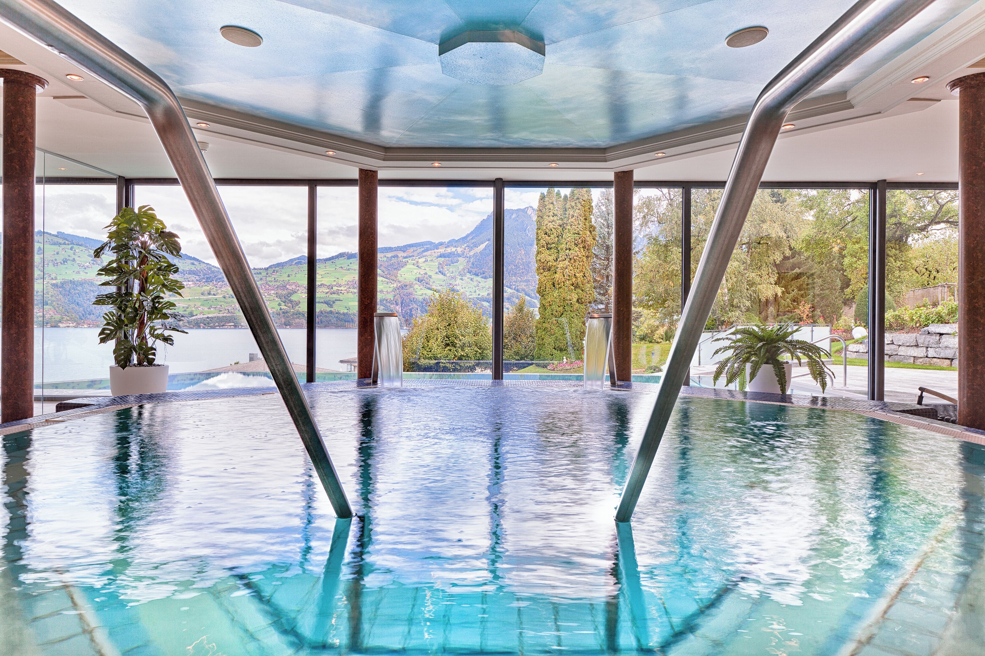An indoor swimming pool with a view of mountains and a clear sky.
