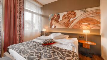 Une chambre d’hôtel avec un lit, une table de chevet, une lampe et une grande œuvre d’art accrochée au mur.