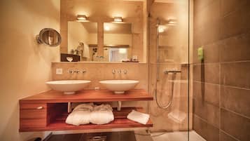 A modern bathroom with two sinks, a large mirror, and a glass-enclosed shower.
