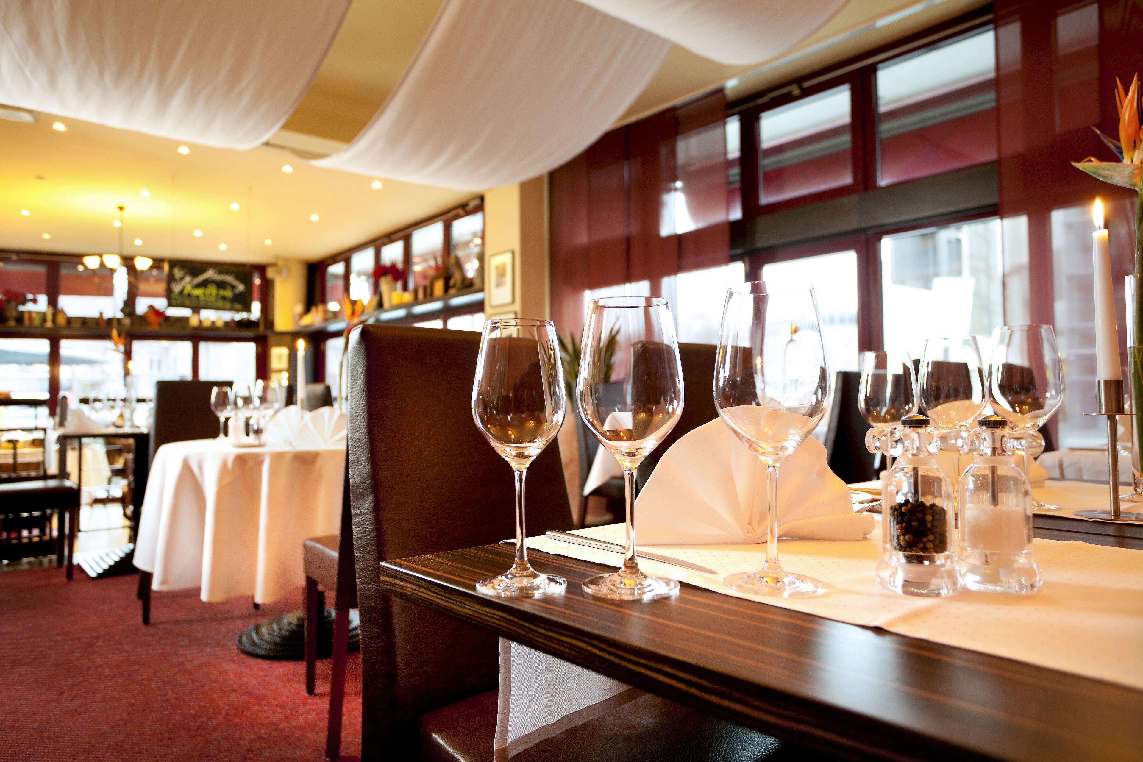 Een restaurant met gedekte tafels, wijnglazen en een kaars.