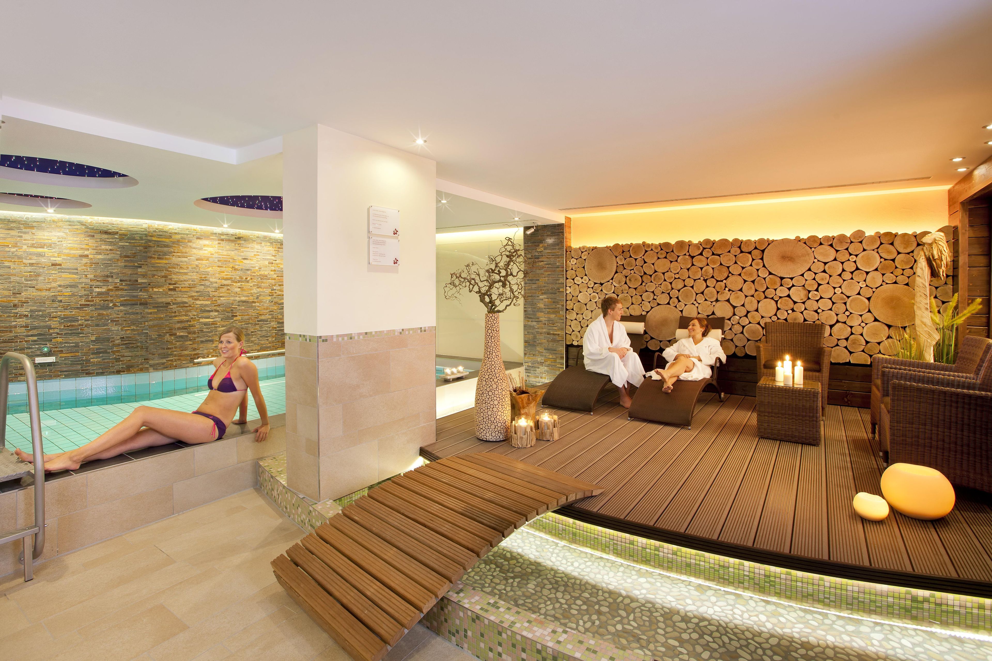 A spa area with a pool, wooden seating, and a wall of logs.