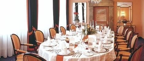 A formal dining room with a round table set for a meal, surrounded by wooden chairs.