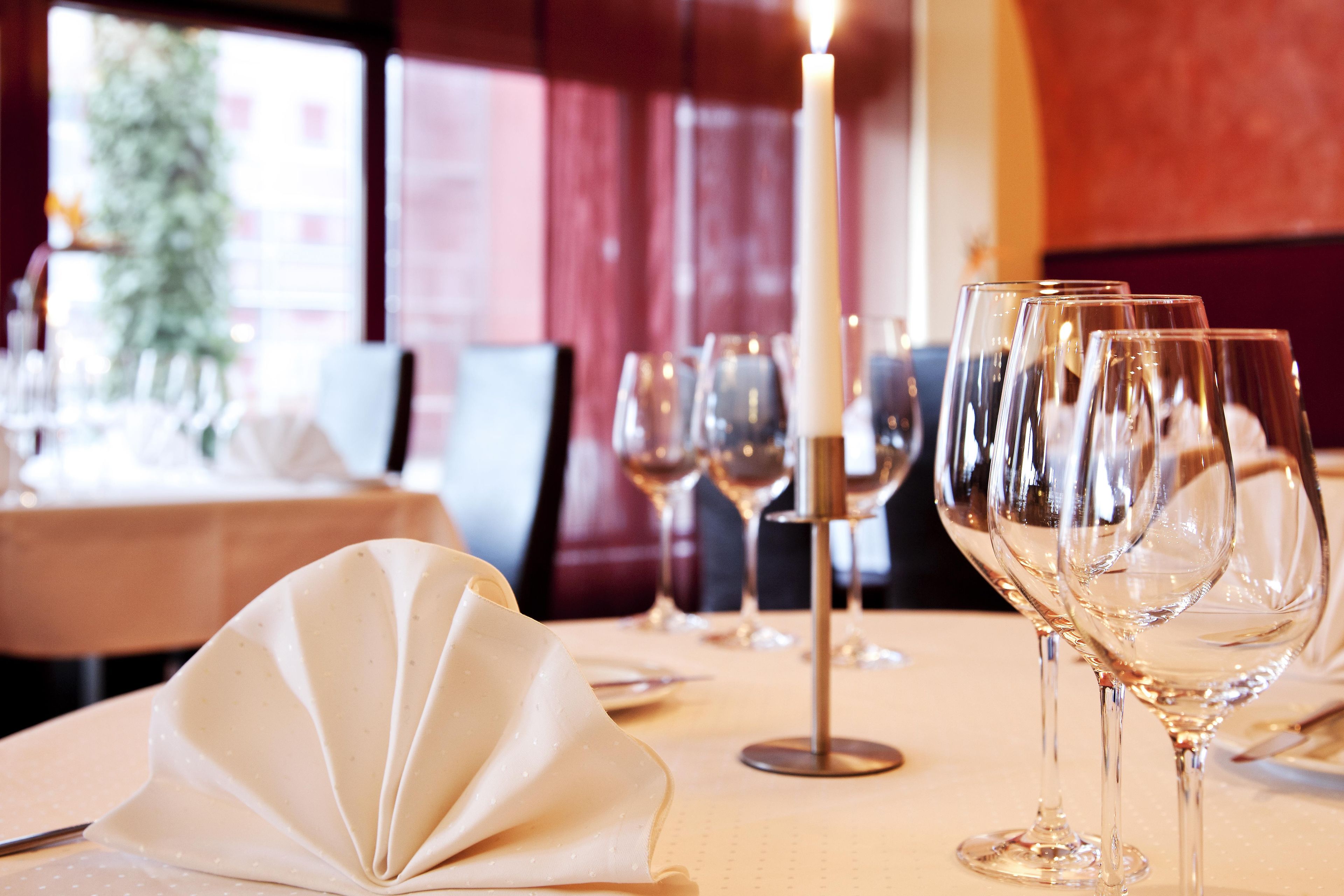 Ein Esstisch mit gedecktem Tisch, Kerzenarrangements, klarem Glas und gefaltetem Servietten.