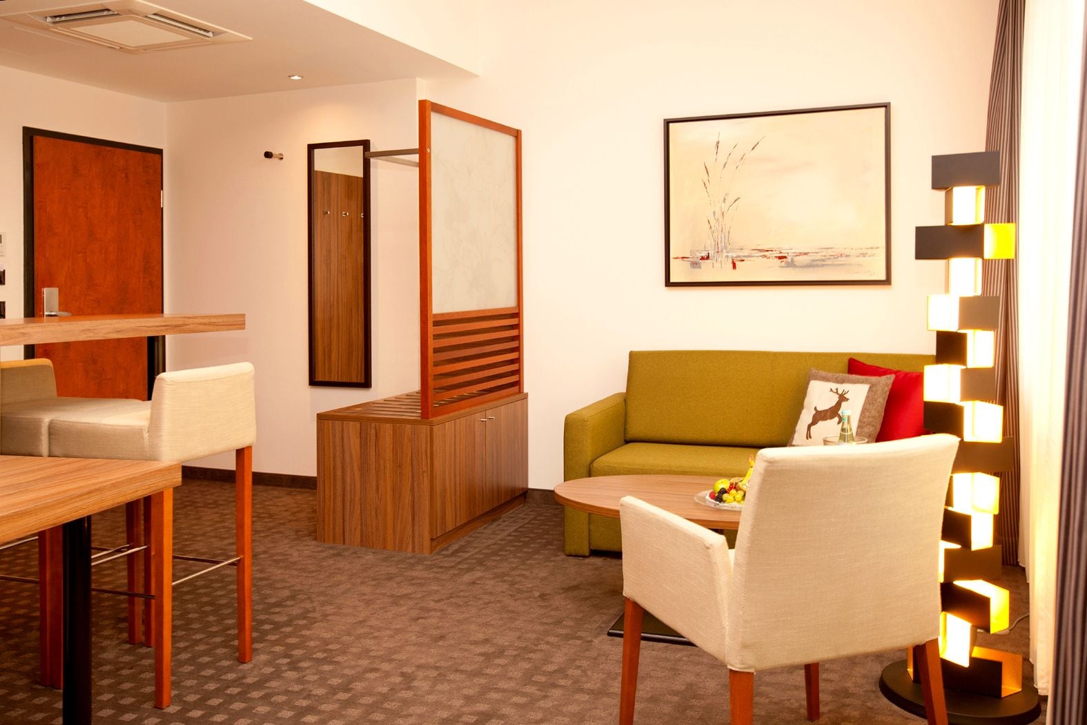 Ein modernes Hotelzimmer mit Essbereich, einer Sitzecke und einem Gemälde an der Wand.