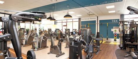Un gimnasio con diferentes máquinas de ejercicio, incluyendo cintas de correr, equipos de pesas y pesas libres.