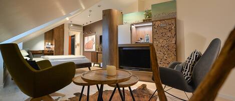 Una sala de estar moderna con chimenea, un comedor con una mesa redonda y un dormitorio con cama y escritorio.