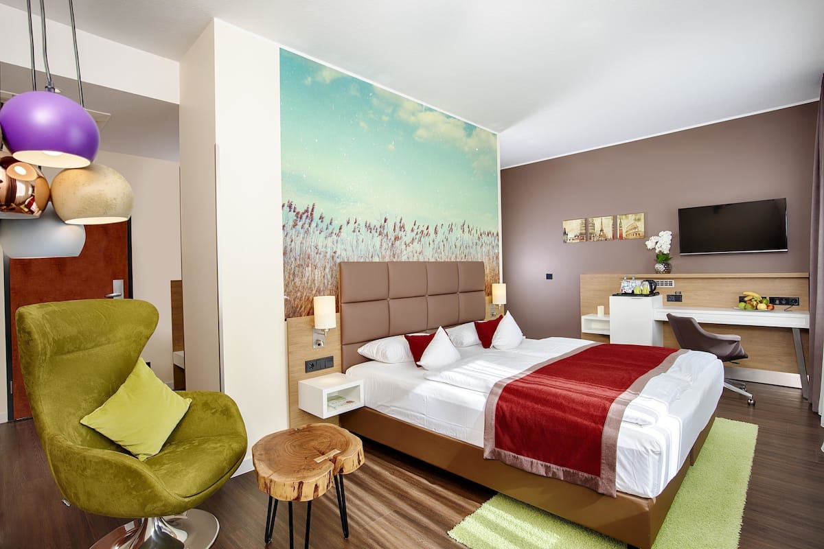Ein modernes Hotelzimmer mit Bett, Schreibtisch, Stuhl und Fernseher.