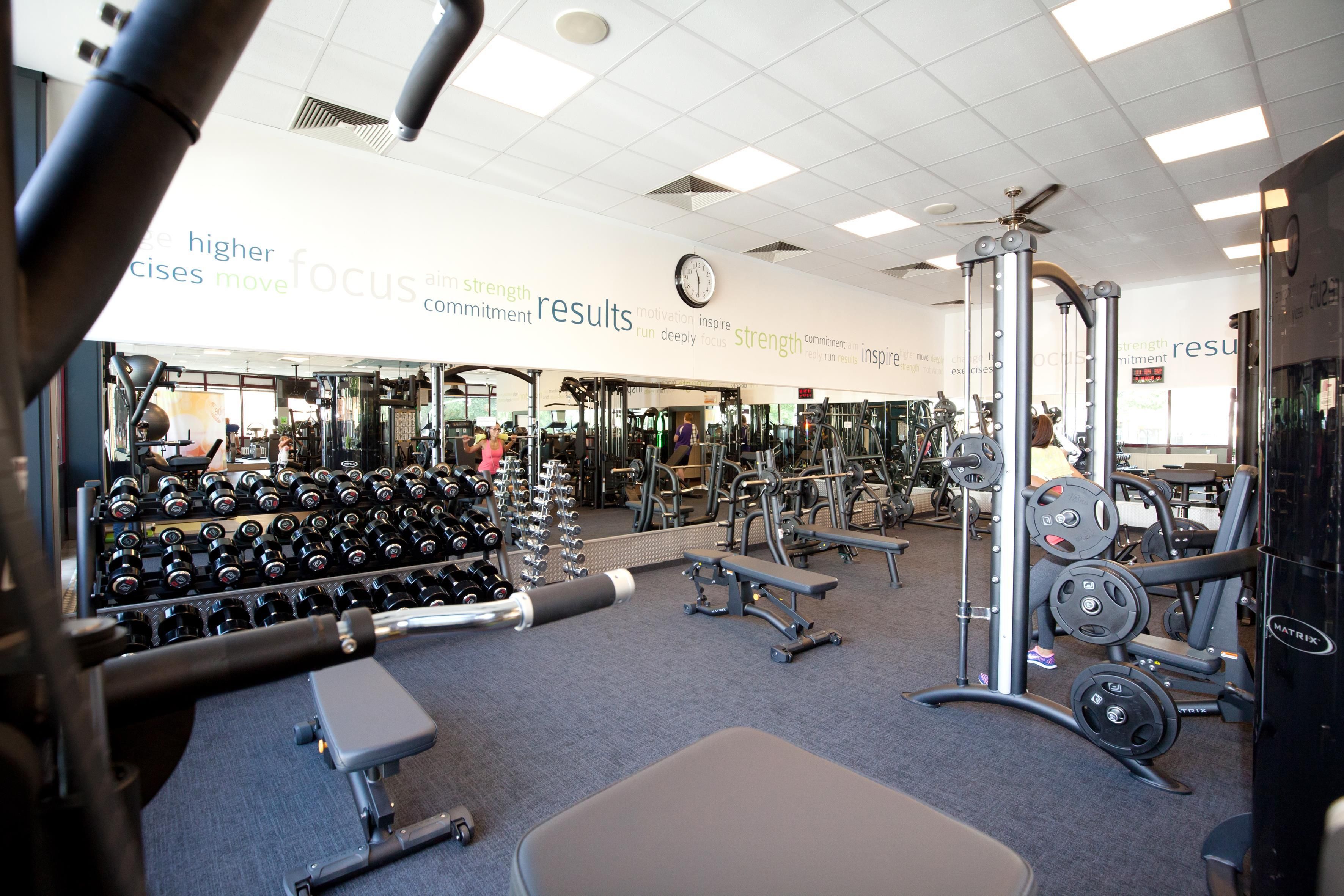 A gym with various exercise equipment, including dumbbells, benches, and weight machines.