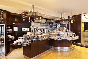 Un área de bufé con diversas opciones de comida, una estación de café y un bar con selección de vinos.