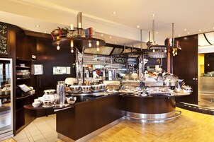 Un área de bufé con diversas opciones de comida, una estación de café y un bar con selección de vinos.