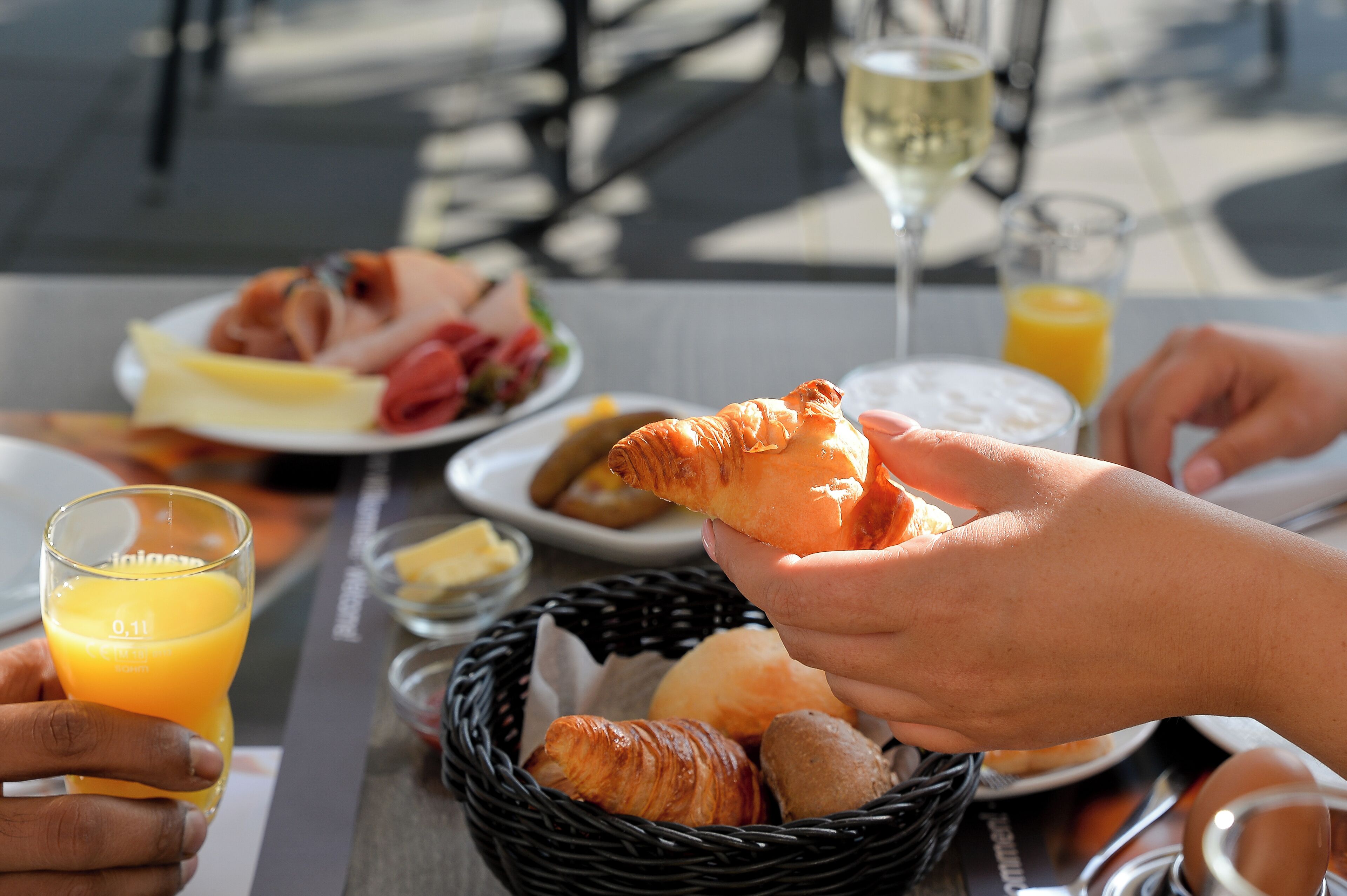 A breakfast setting with croissants, orange juice, and a glass of white wine on a table.