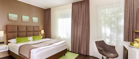 A hotel room with a bed, a desk, a chair, and a view of the outdoors.