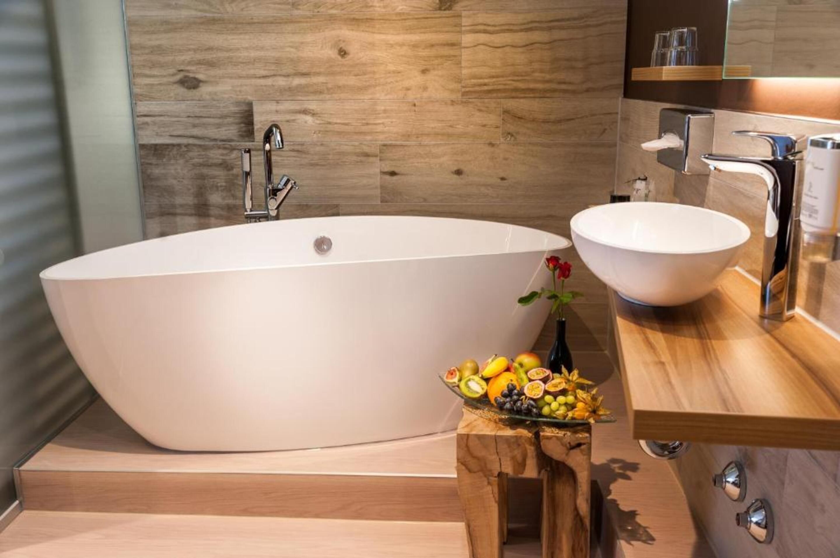 A modern bathroom with a freestanding bathtub, a round sink, and a wooden vanity.