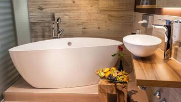 A modern bathroom with a freestanding bathtub, a round sink, and a wooden vanity.