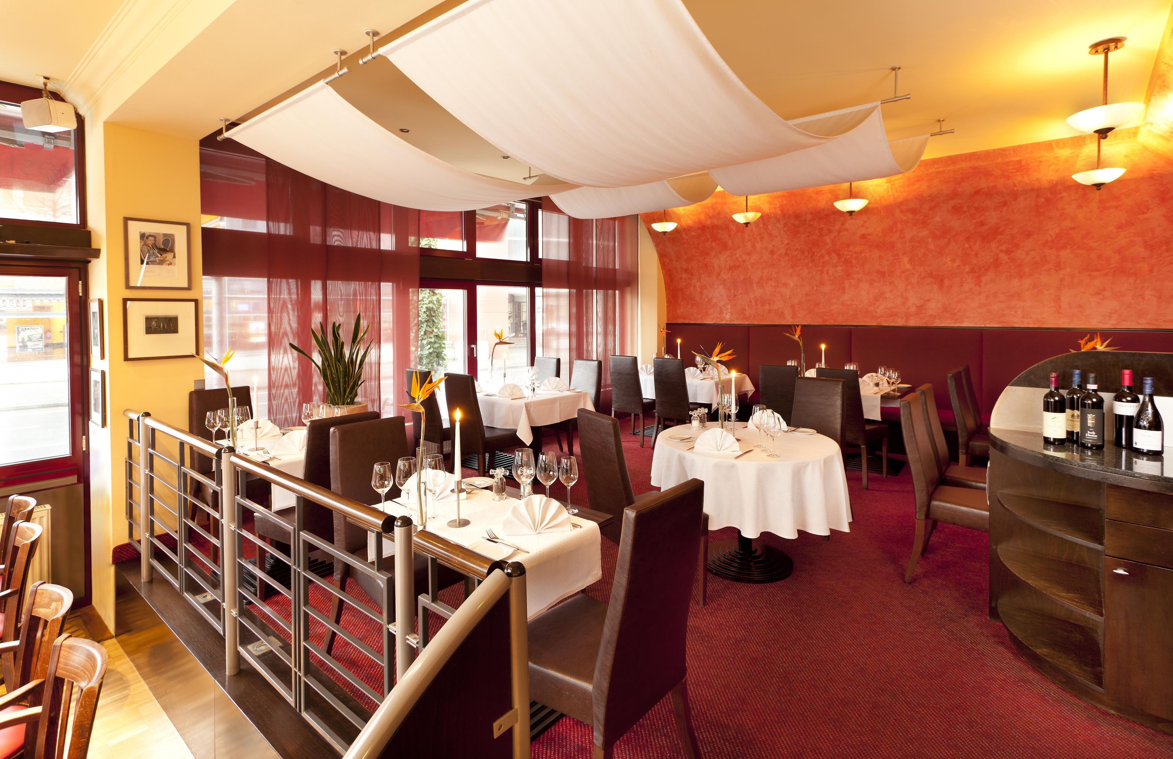 Interno di un ristorante con diversi tavoli, sedie e un'area bar.