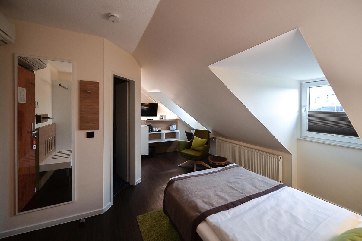 A bedroom with a bed, a chair, a desk, and a television.