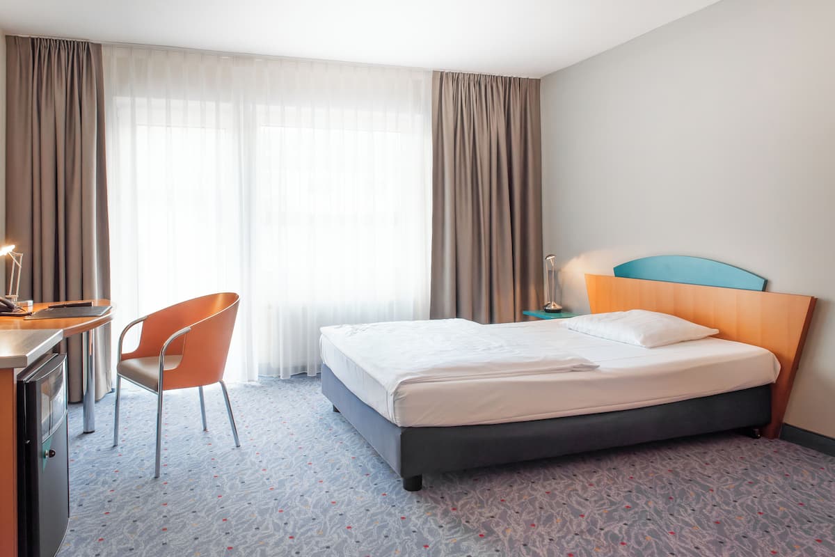 Ein Hotelzimmer mit Bett, Schreibtisch, Stuhl und Nachttisch.