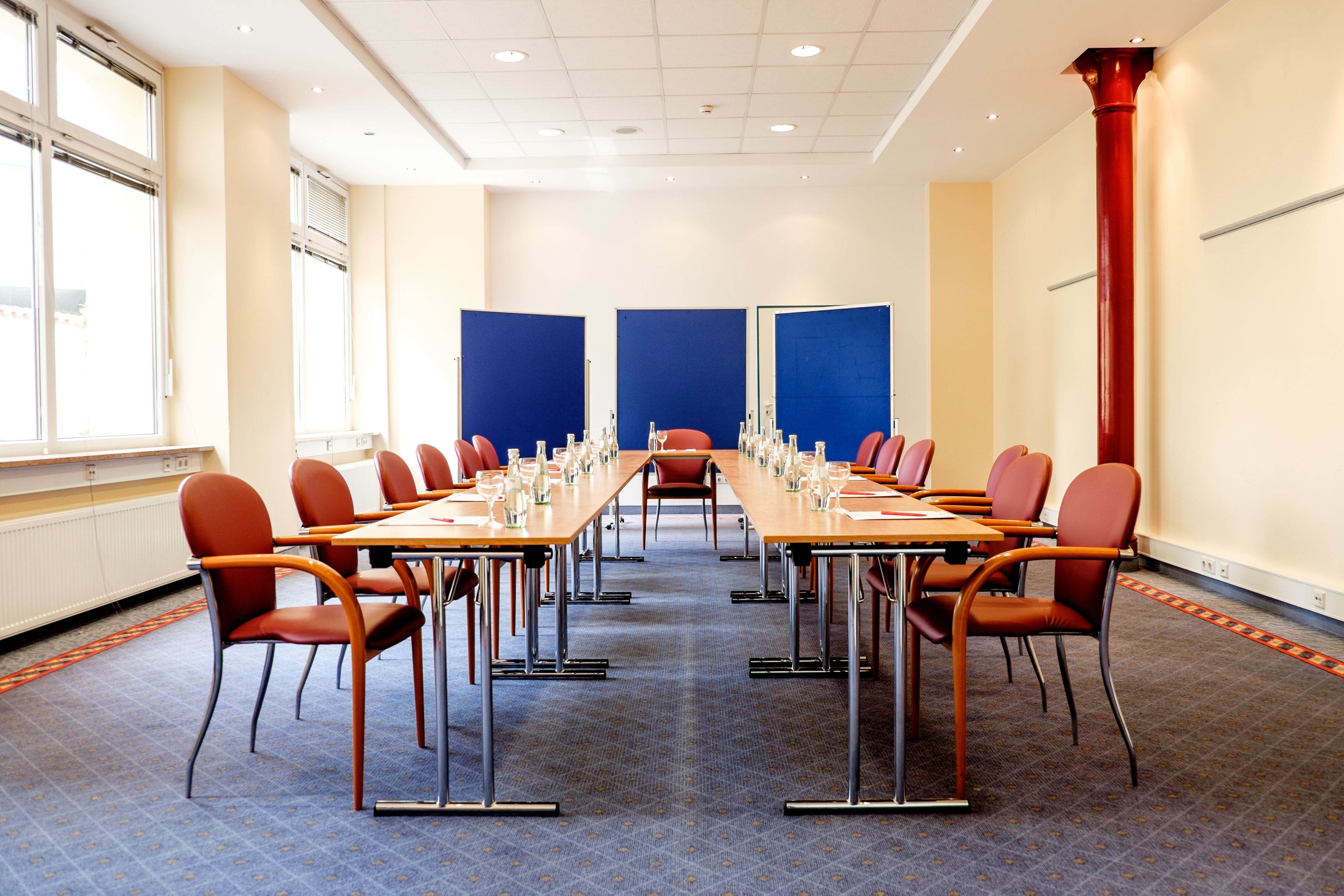 A conference room with a long table, red chairs, and blue partitions.
