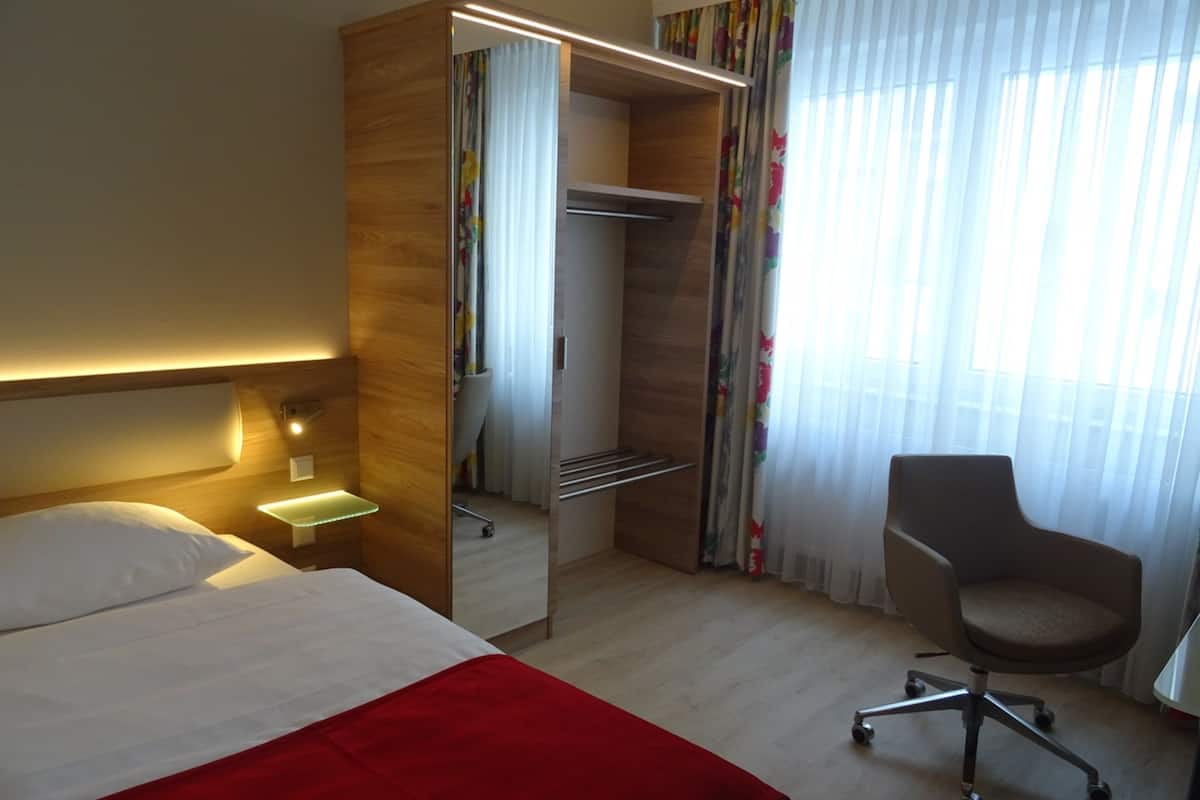 Ein Hotelzimmer mit Bett, Schreibtisch, Stuhl und Kleiderschrank.