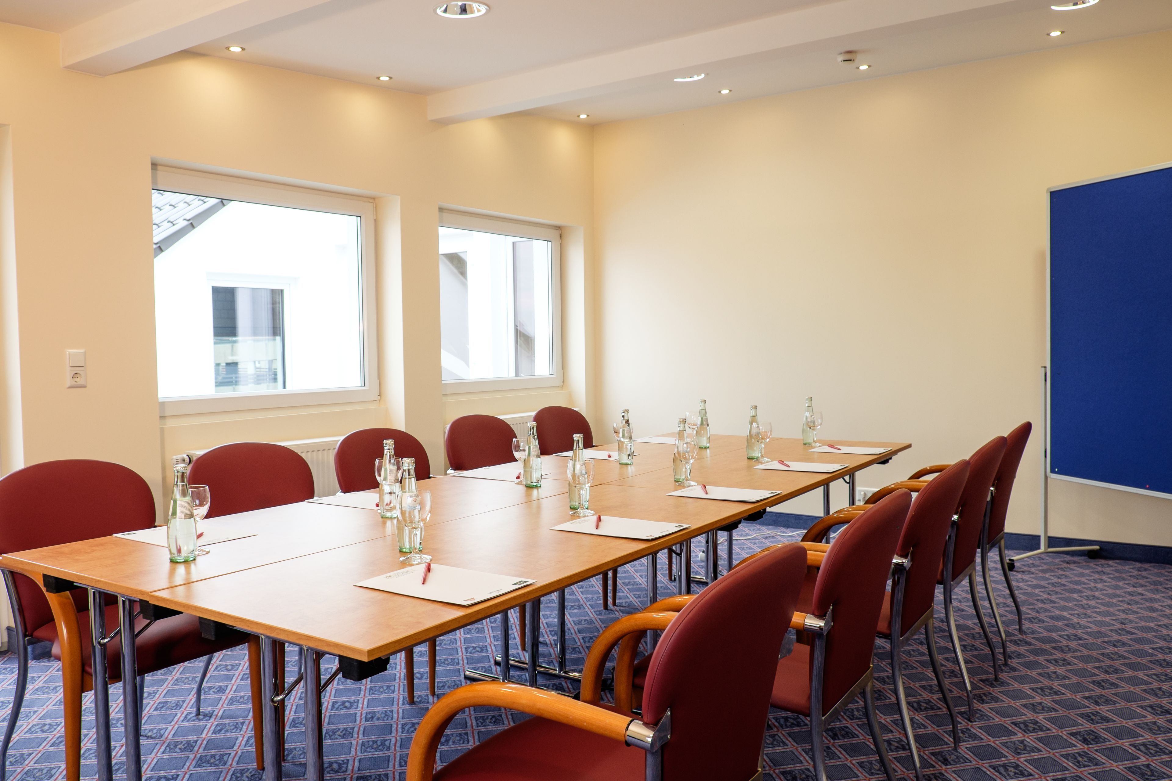 A conference room with a long table, red chairs, and large windows.