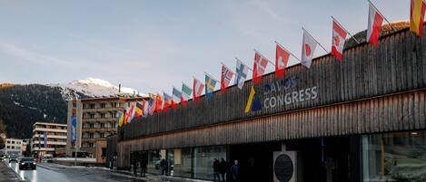 A building with multiple flags, a wooden facade, and a sign that reads "CAVOS CONGRESS".