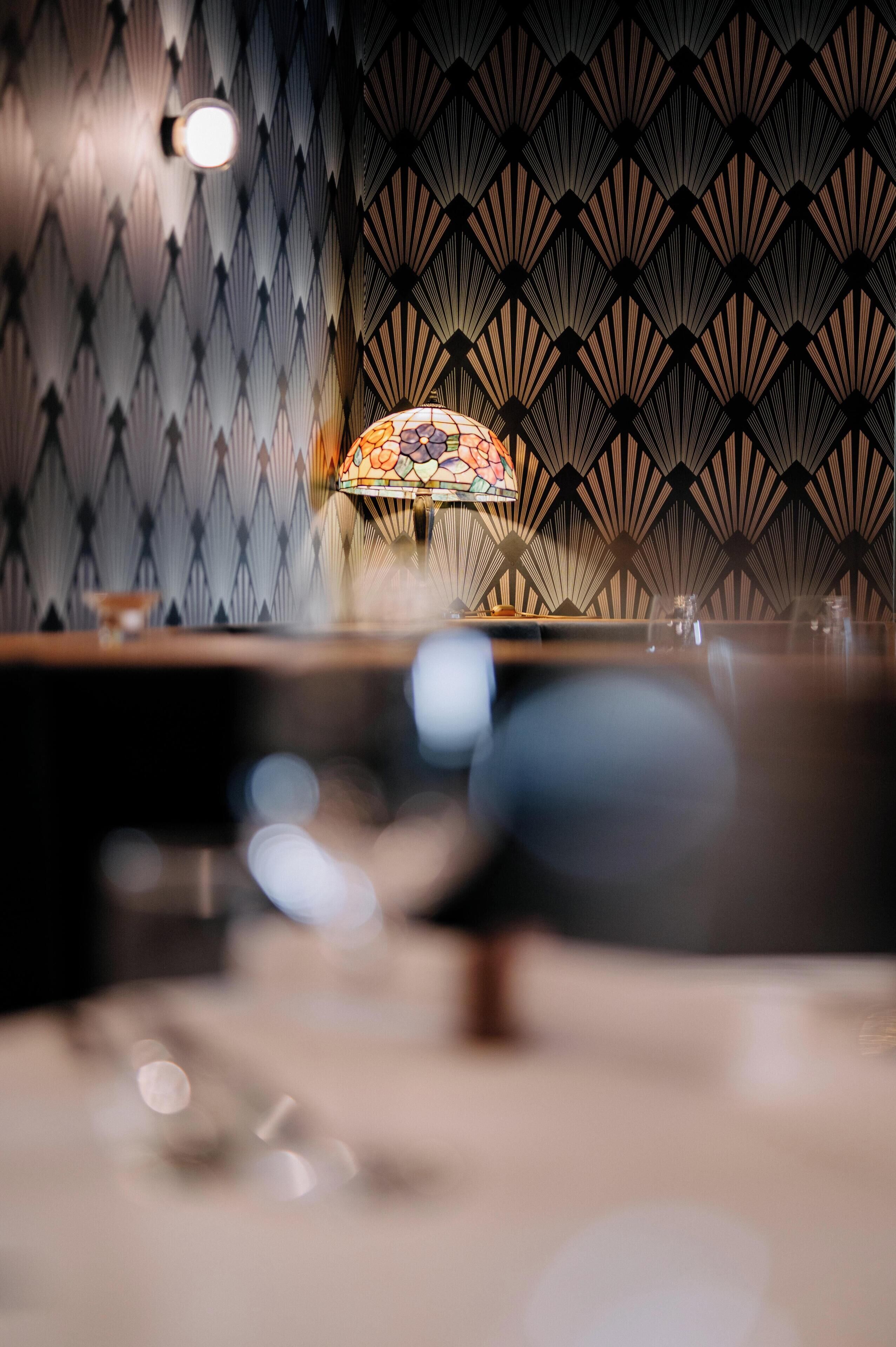 A room with a patterned wall and a stained glass lamp.