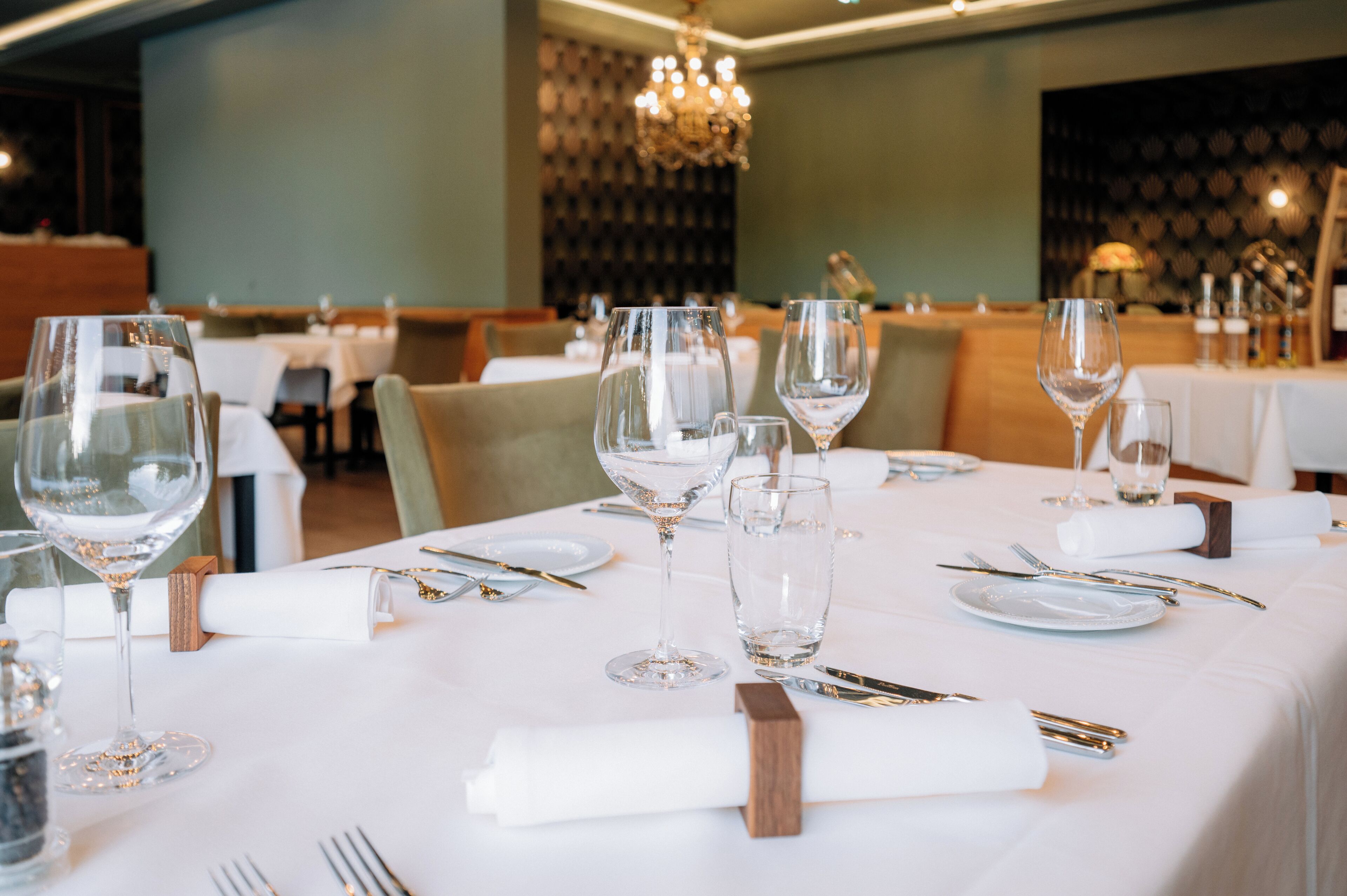 A restaurant dining area with tables set for a meal, including wine glasses, plates, and cutlery.
