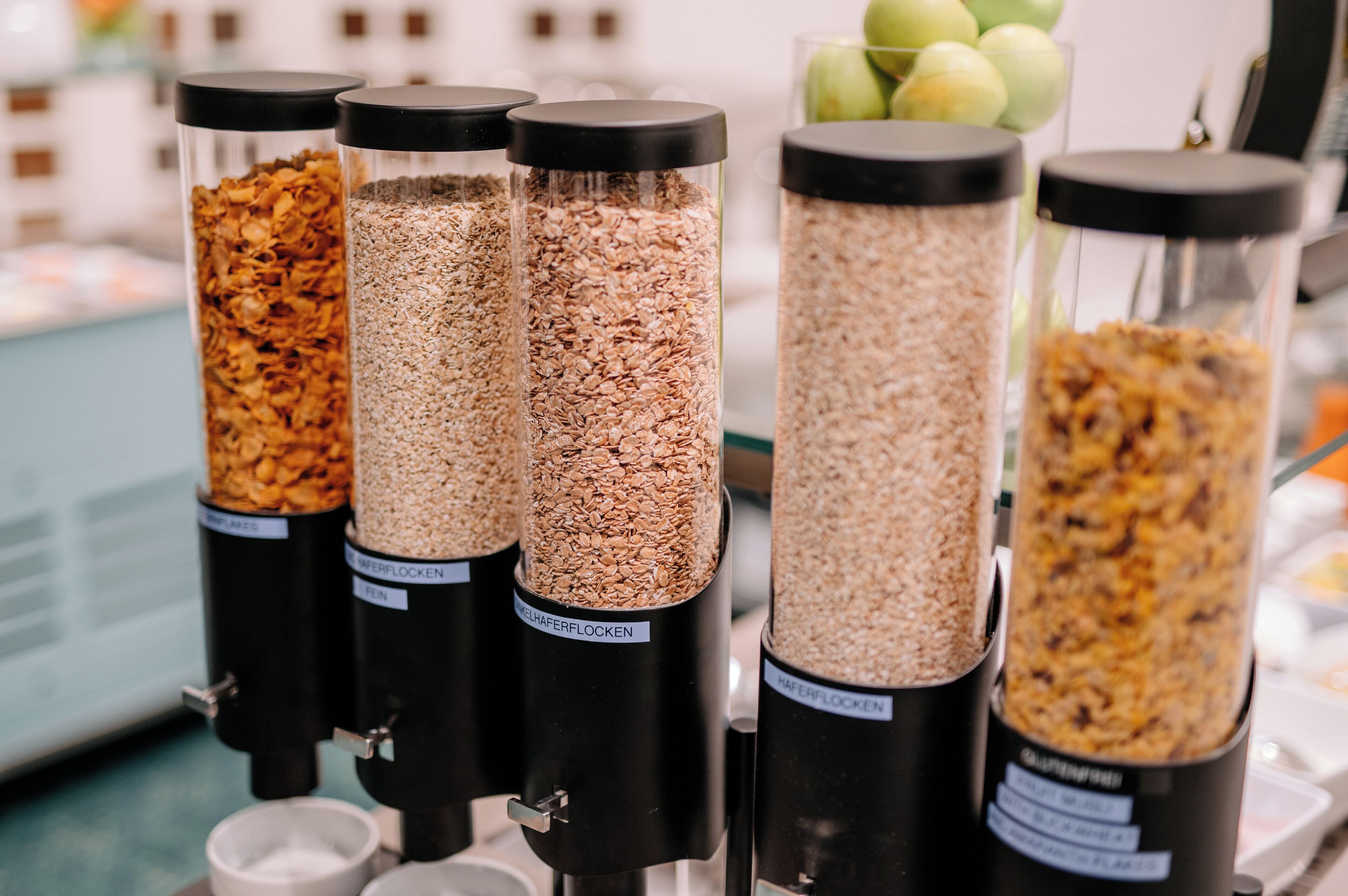 Four glass containers with different grains labeled in German.