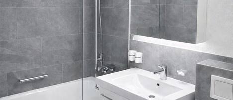 A modern bathroom with a bathtub, a sink, and a mirror.