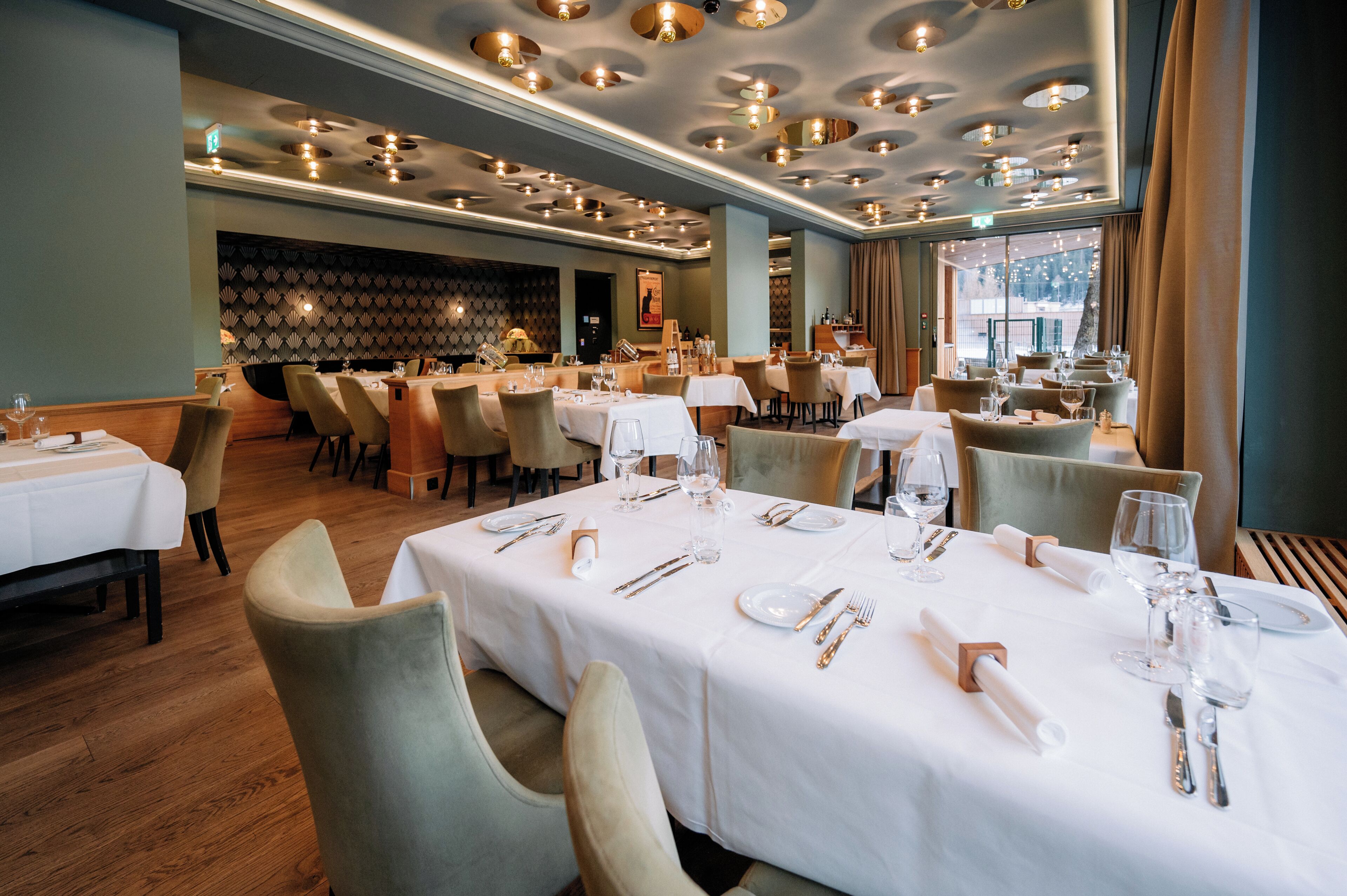 A restaurant with multiple tables set for dining, featuring white tablecloths and neatly arranged cutlery.