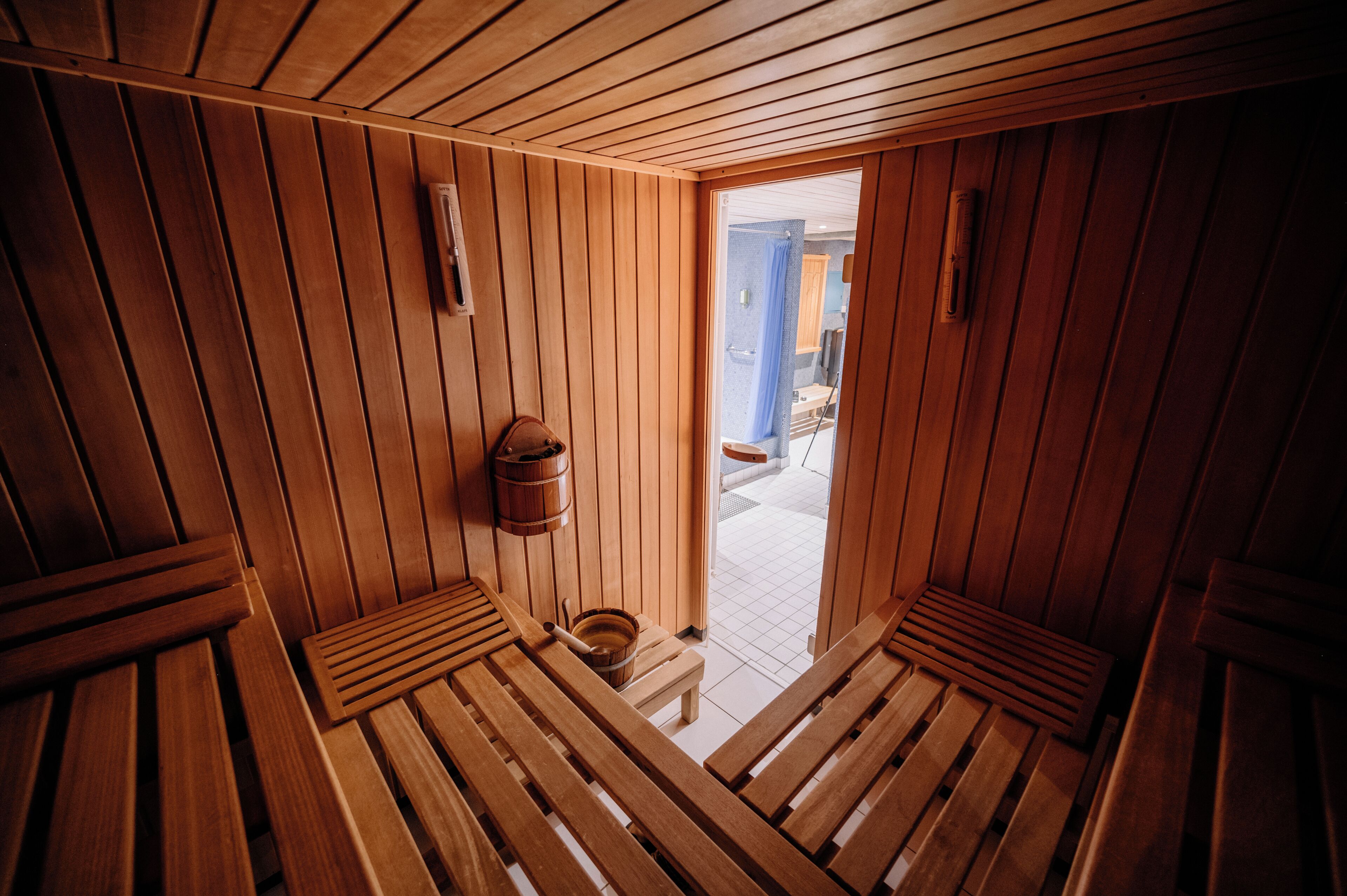 Un sauna en bois avec des bancs et un seau en bois.