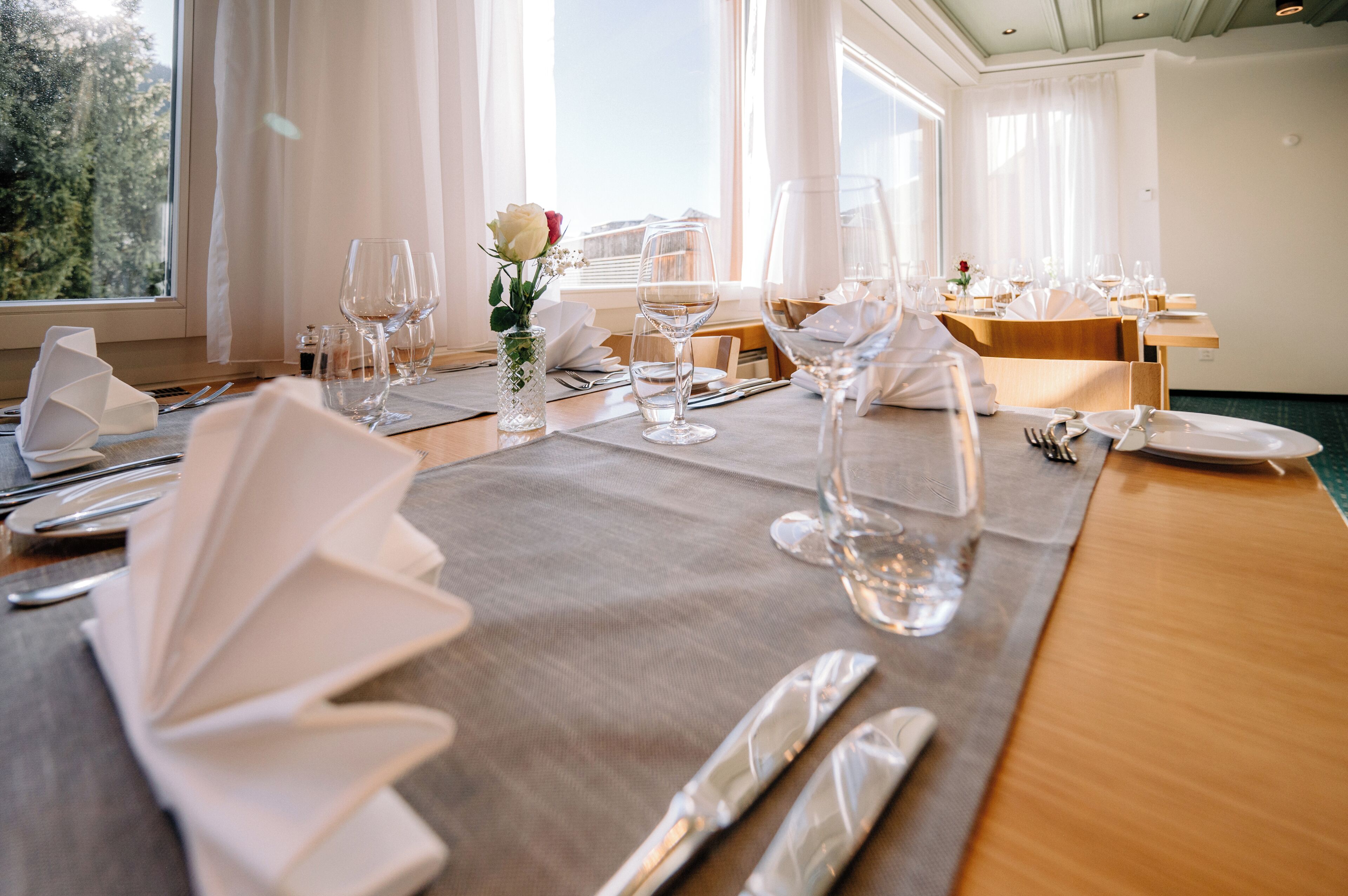 A dining table set for a meal with white tablecloths, clear glassware, and neatly folded napkins.